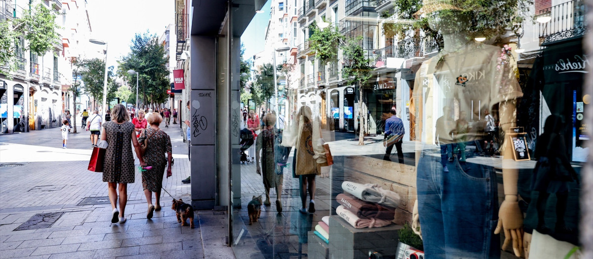 Varias personas pasan por delante de un escaparate de una tienda de ropa en Madrid.