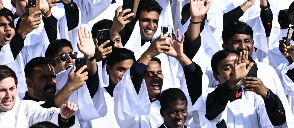 Los sacerdotes saludan mientras el Papa León XIV saluda a la multitud desde el papamóvil antes de la Santa Misa de inicio de su pontificado