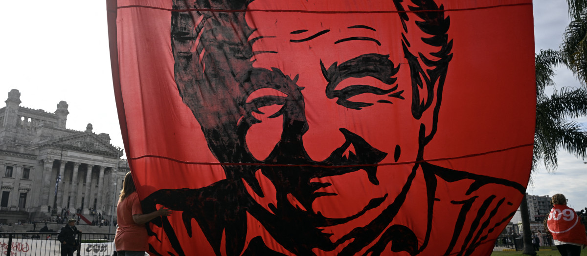 Una mujer abraza una enorme pancarta con la imagen del expresidente uruguayo José "Pepe" Mujica, colgada frente al Palacio Legislativo