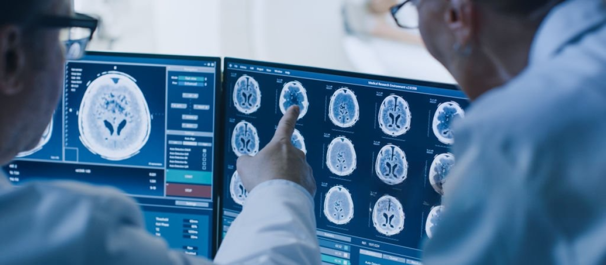 Un médico y un radiólogo discuten el diagnóstico en unos monitores que muestran resultados de las exploraciones del cerebro