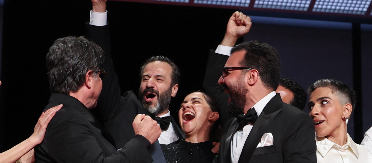 El director, guionista y productor iraní Jafar Panahi (izq.) y su equipo celebran en el escenario tras ganar la Palma de Oro