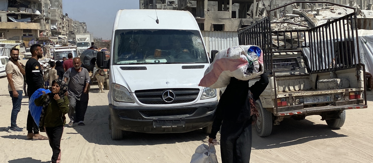 Una mujer camina con un saco en la cabeza y arrastra otro por una carretera utilizada por desplazados que huyen de Khan Yunis hacia el oeste, en dirección a Al-Mawasi, en el sur de la Franja de Gaza