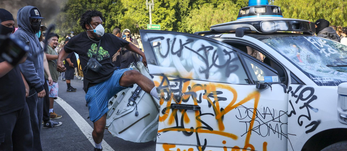 LOS ANGELES (United States), 08/06/2025.- A protester vandalizes a Waymo self driving car during immigration raid protests in Los Angeles, California, USA, 08 June 2025. US President Donald Trump has deployed 2,000 National Guard troops, despite not receiving a request from the state of California for any additional assistance, following large protests against ongoing immigration enforcement raids in the Los Angeles area over the last couple of days. (Protestas) EFE/EPA/ALLISON DINNER