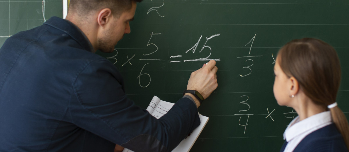 Un profesor enseña a su alumna una operación matemática
