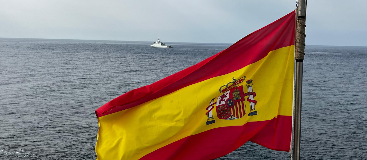 La bandera de España ondea en la isla de Alborán; al fondo, el buque de acción marítima Furor de la Armada española