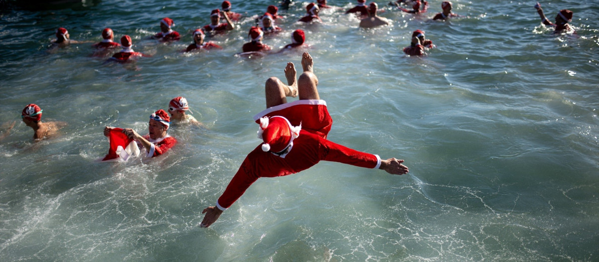 Un hombre vestido de Papá Noel salta al agua en Barcelona, durante la 114ª Copa Nadal