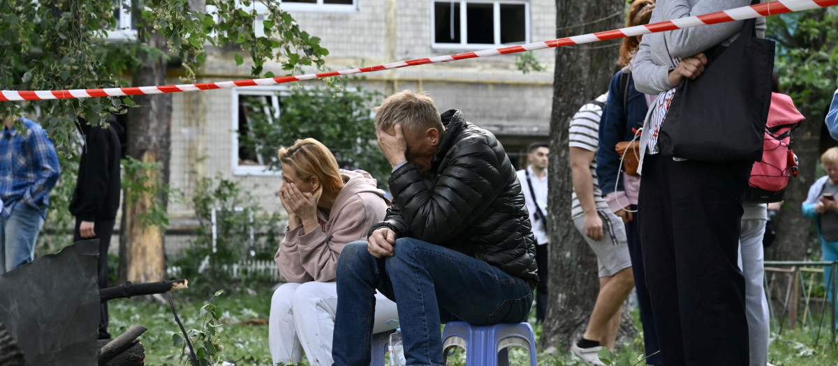 Residentes reaccionan mientras los rescatistas ucranianos realizan labores de búsqueda y rescate en un edificio residencial gravemente dañado tras el ataque con misiles rusos en Kiev