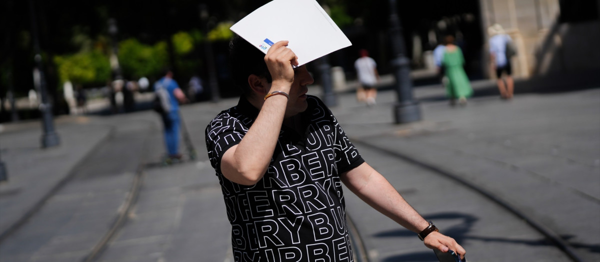 Un hombre se protege del sol con una carpeta en Sevilla
