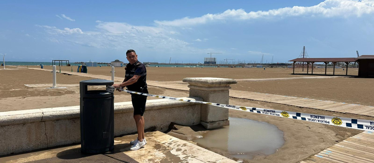 Un policía local cierra una playa de Valencia ante el riesgo meteorológico