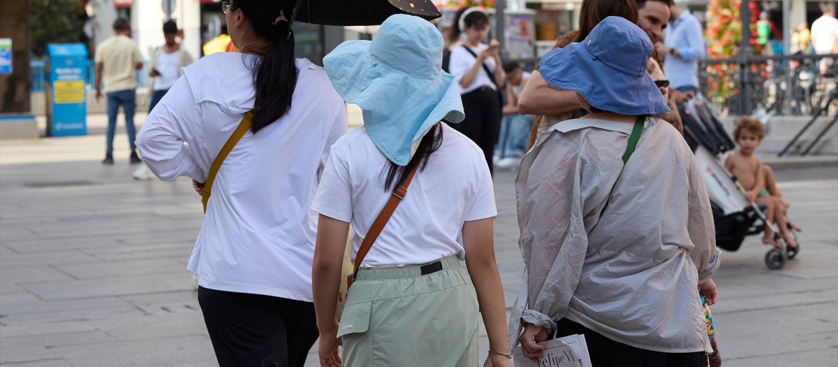 Varias personas se protegen de las altas temperaturas en Madrid
