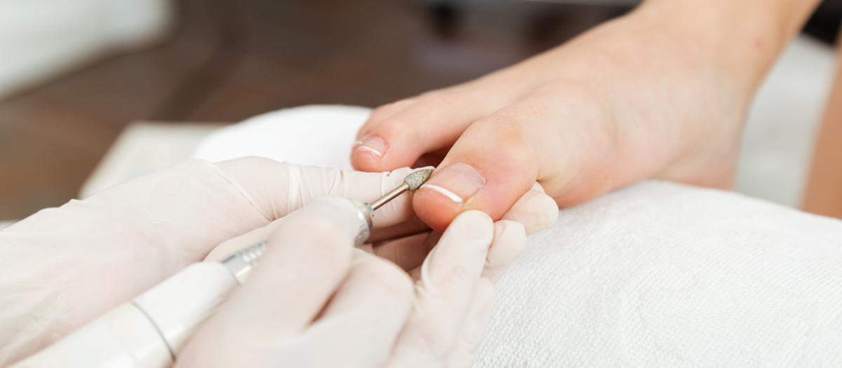 Portrait of young woman doing pedicure in salon. Beauty concept.