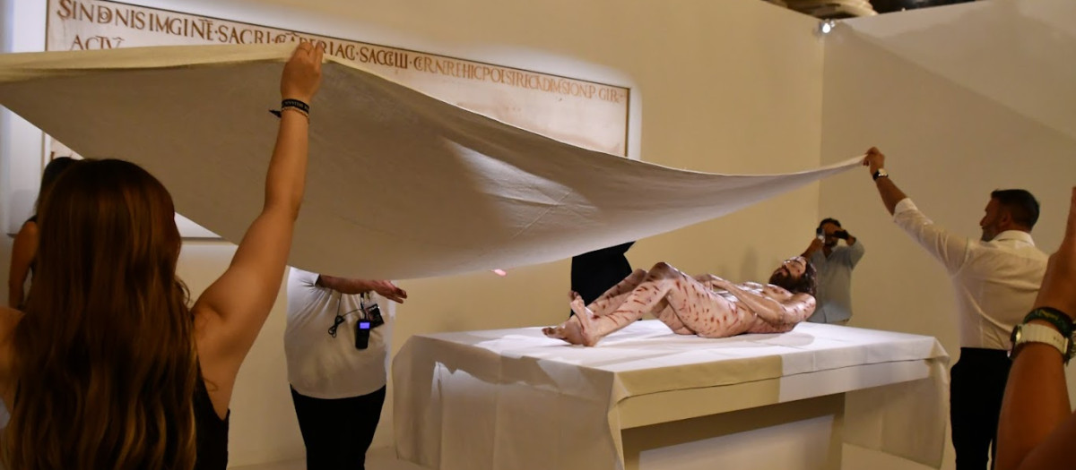 Varios operarios cubren la escultura hiperrealista con un paño