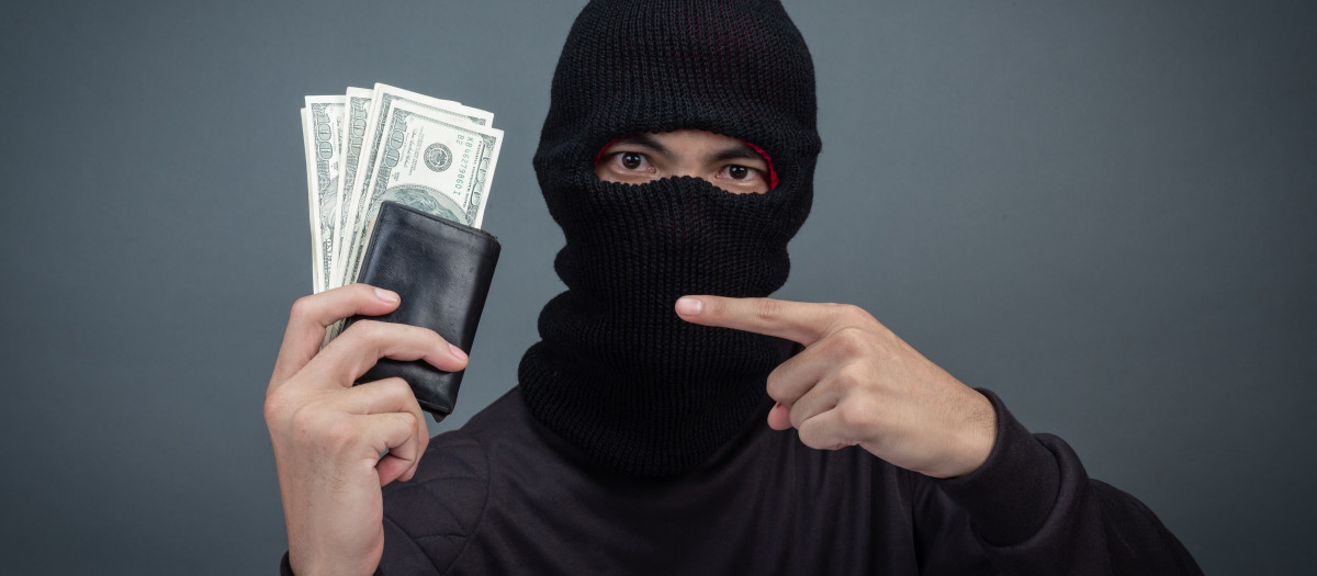 Thief wears a black hat with a stolen purse on a gray background.