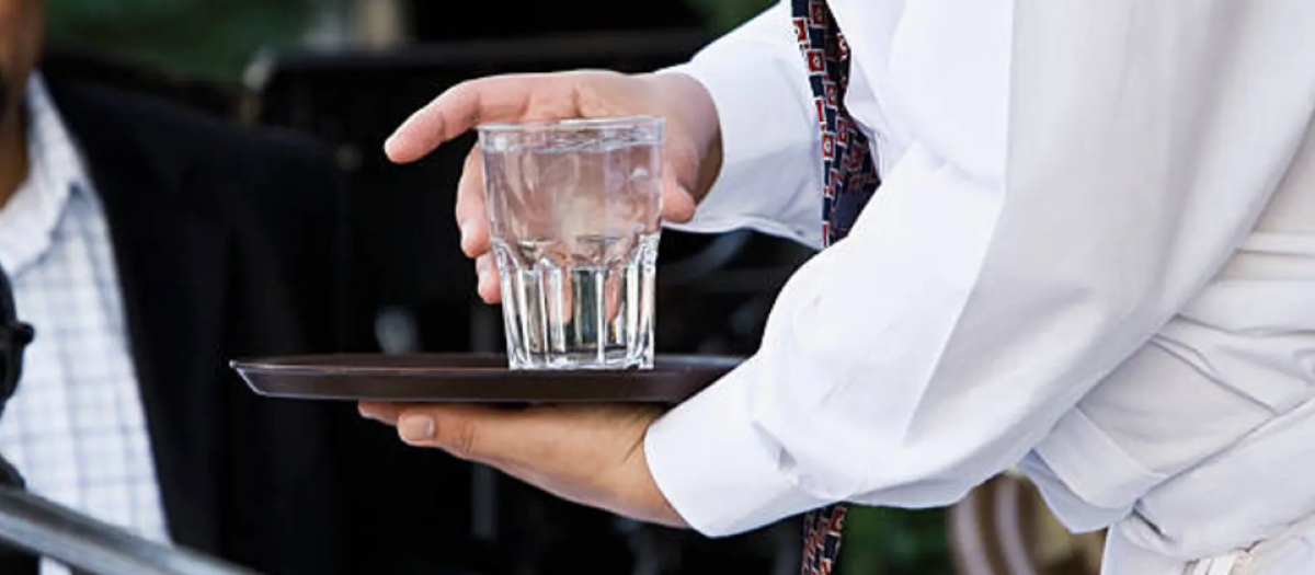 Imagen de un camarero sirviendo un vaso de agua a un cliente
