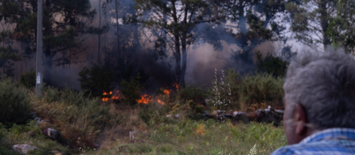 Una persona observa el fuego, a 5 de agosto de 2025, en Ponteceso, A Coruña, Galicia (España). Un nuevo incendio en el municipio coruñés de Ponteceso ha obligado este martes a desalojar a vecinos de la parroquia de Corme Aldea. Fuentes de la Consellería do Medio Rural explican a Europa Press que en la zona no pueden actuar medios aéreos "debido a las condiciones meteorológicas" en una jornada de fuerte viento del nordeste, lo que supondría "un riesgo" para los trabajadores.

Gustavo de la Paz / Europa Press
05 AGOSTO 2025;INCENDIO;FUEGO;GALICIA;GALIZA;
05/8/2025