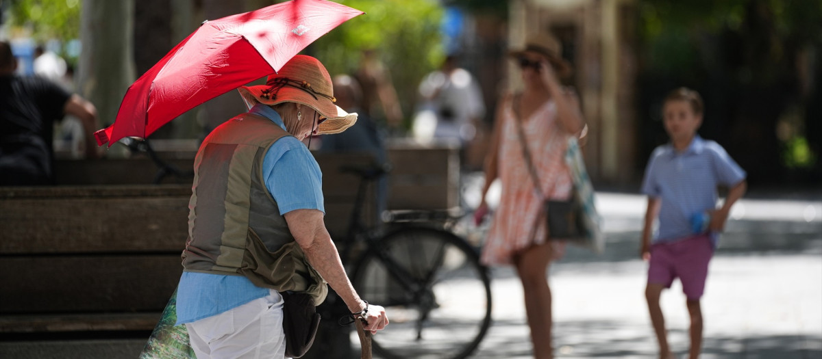 (Foto de ARCHIVO) Una mujer con sombrero y sombrilla paseando por puerta de Jerez