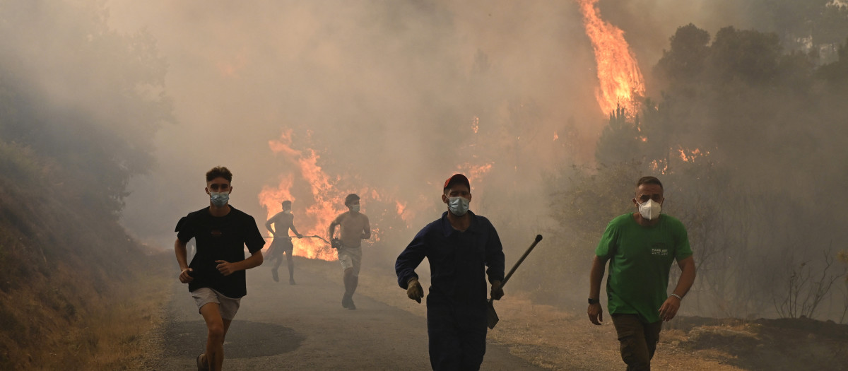 Personas corren por una zona quemada durante un incendio forestal cerca del pueblo de Larouco, en la provincia de Ourense.