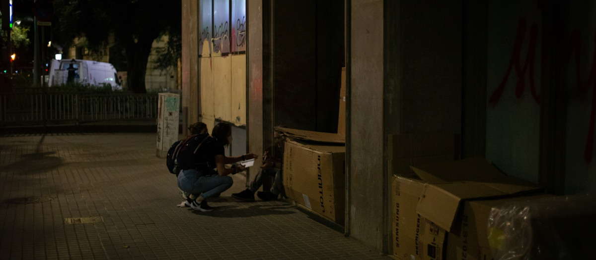 Una voluntaria de la Fundación Arrels habla con personas sin techo en Barcelona