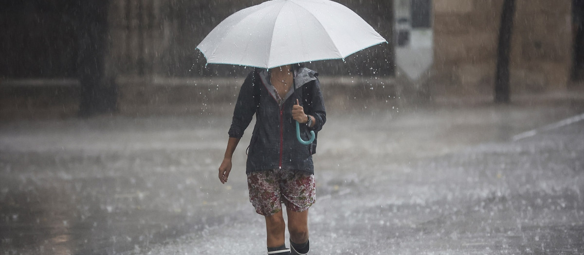 Una persona camina con un paraguas bajo la lluvia