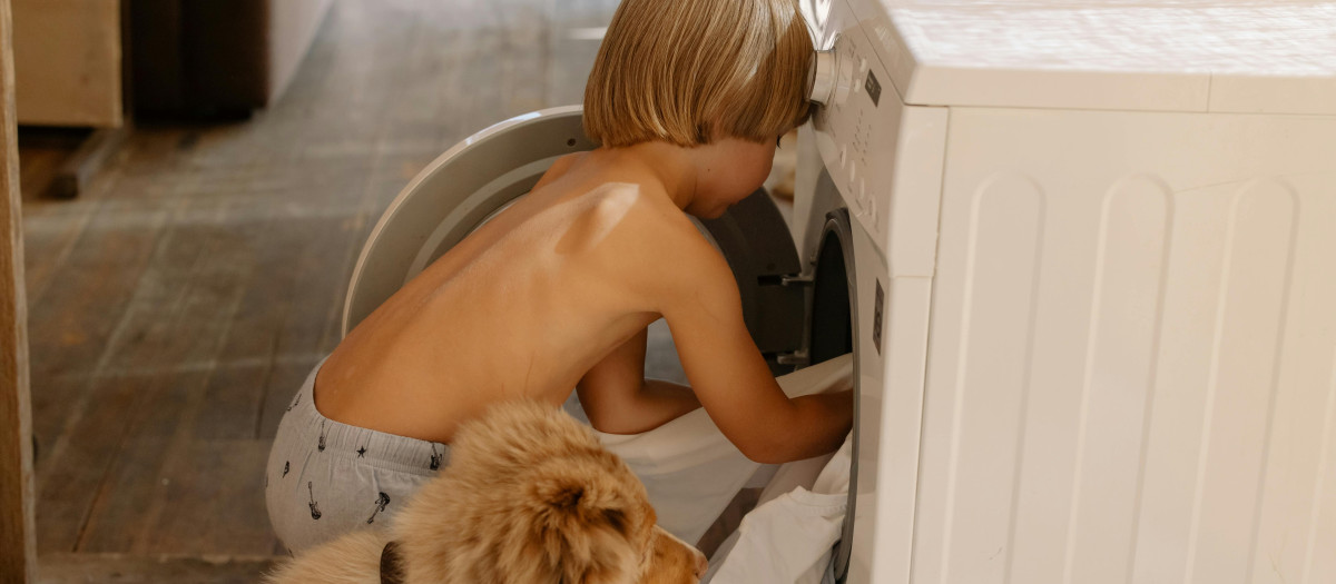 Un niño cargando su ropa sucia en la lavadora