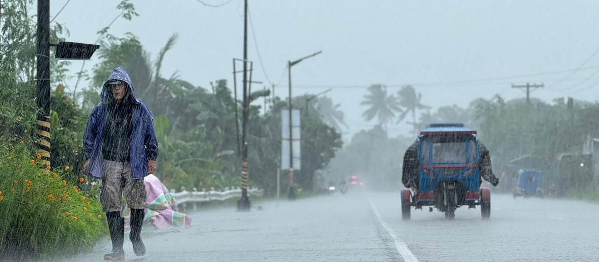 Un hombre camina por una carretera en medio de fuertes lluvias causadas por el supertifón Ragasa en la ciudad de Lal-loc