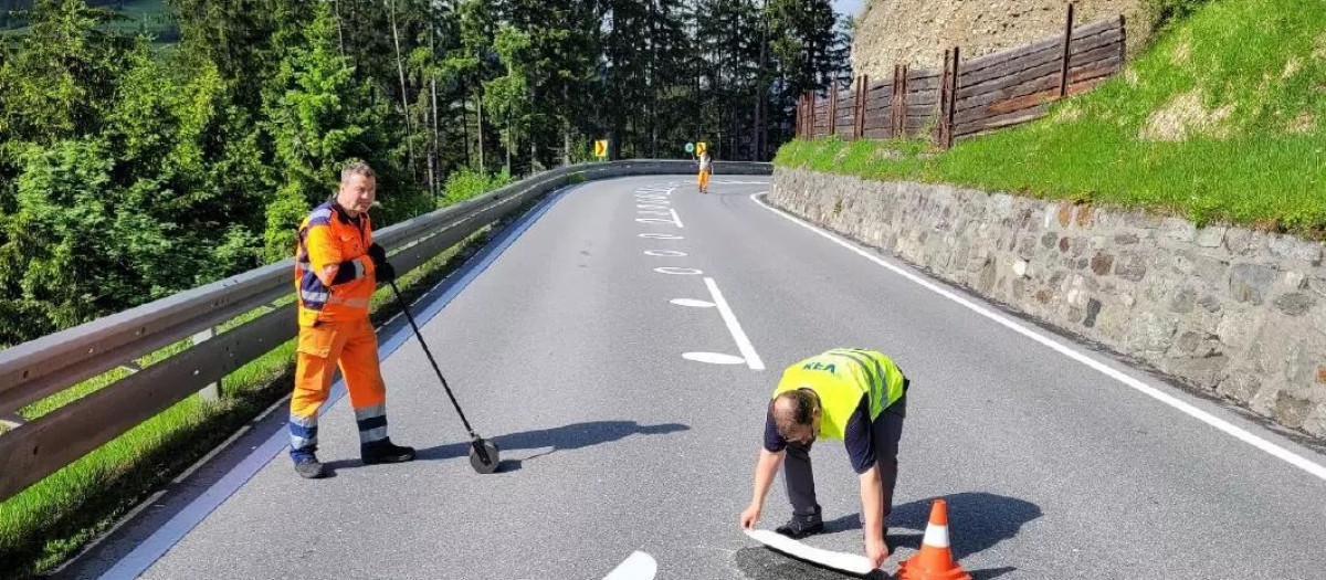 Los operarios de carretera pintando las esferas sobre el asfalto