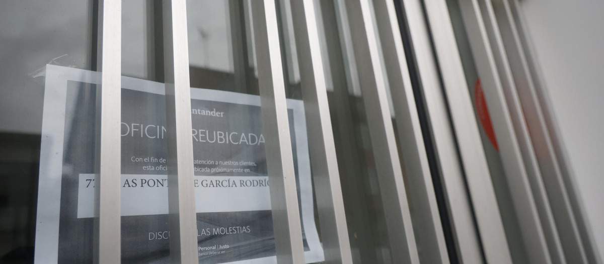 A CAPELA (A CORUÑA), 25/10/2025.- Vista de la oficina de Banco Santander cerrada en el pueblo de A Capela, donde un cartel en su puerta avisa del traslado del servicio de oficina a la población grande más cercano. El foco suele alumbrar a las personas mayores, pero el fenómeno creciente de la exclusión bancaria no entiende de edades, especialmente en el rural, donde una tecnología de acceso más dificultoso o la lejanía de las áreas urbanas complica la equiparación de derechos con respecto a los vecinos de cualquier ciudad. EFE/ Kiko Delgado