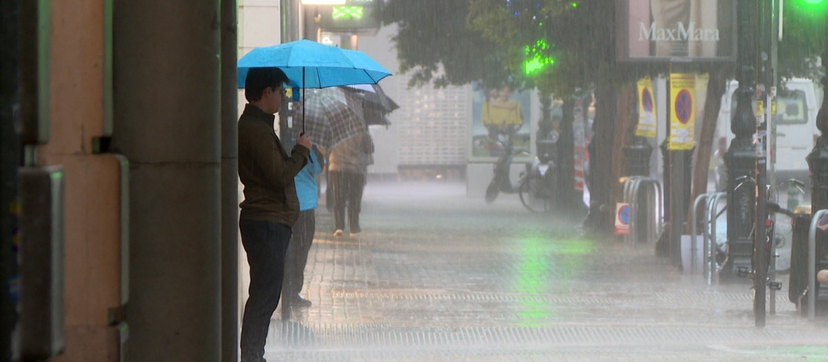 Imagen de una persona resguardándose de la lluvia en Valencia