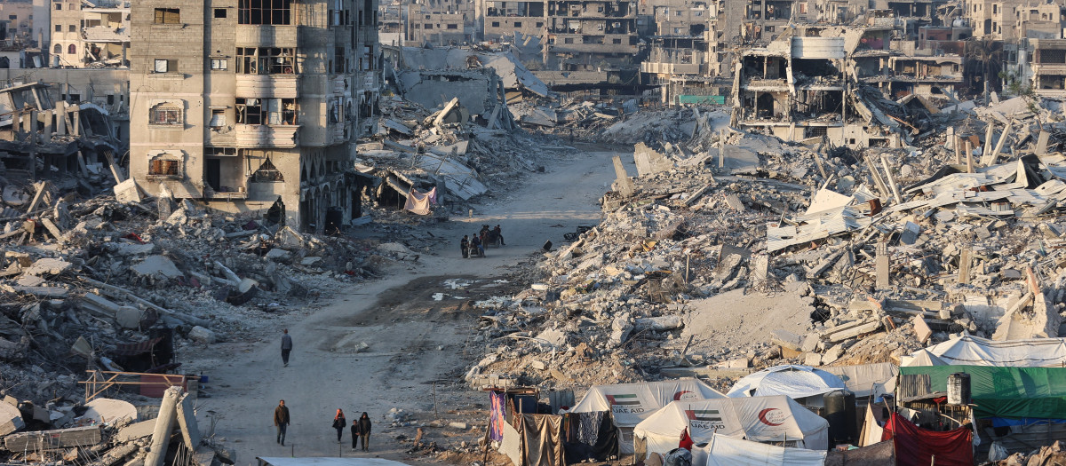 Palestinos caminan junto a los escombros de los edificios destruidos en el barrio Sheikh Radwan de la ciudad de Gaza