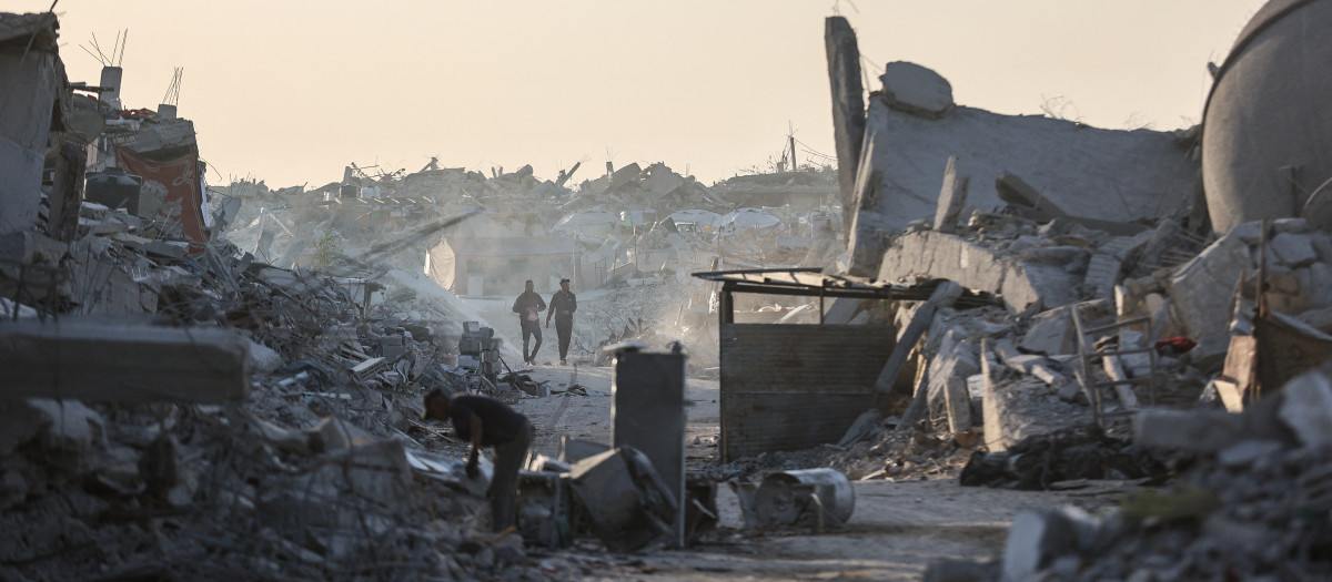 Palestinos caminan entre los escombros de los edificios destruidos en el barrio Sheikh Radwan de la ciudad de Gaza