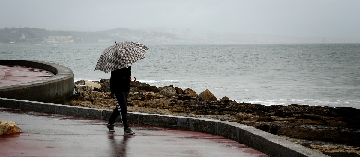 Una persona con un paraguas bajo la lluvia en Lisboa, Portugal