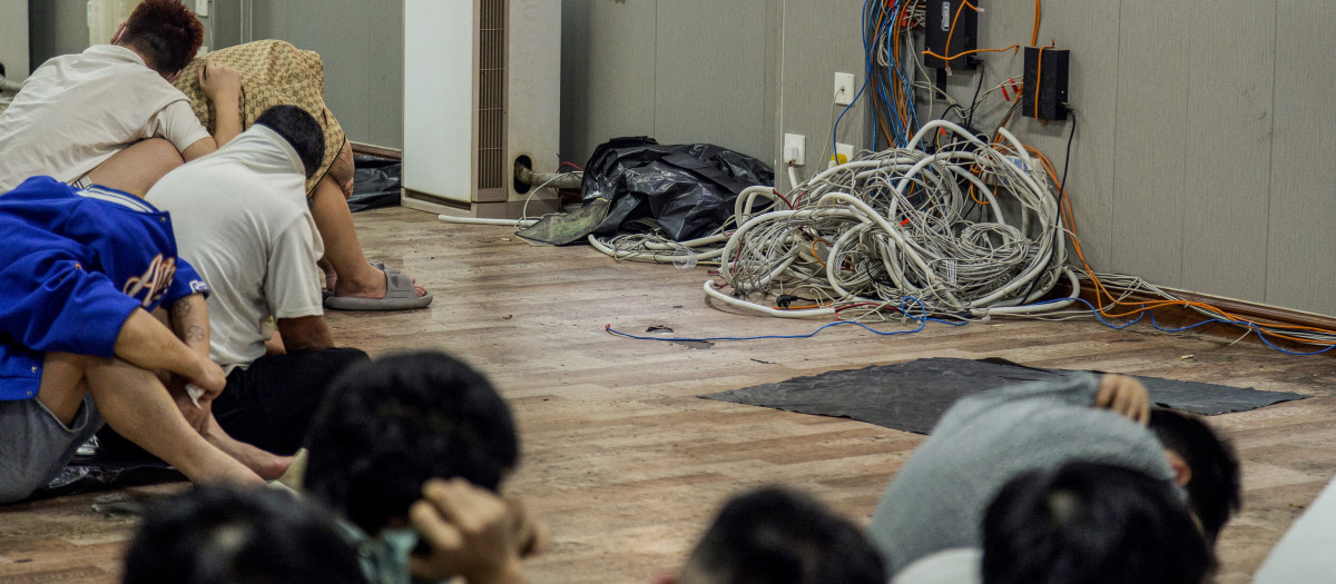 Supuestos trabajadores de centros de estafas y víctimas se sientan junto a aparatos informáticos y electrónicos desmantelados durante una operación de represión realizada por la Fuerza de Guardia Fronteriza Karen (BGF) contra actividades ilícitas en Shwe Kokko, en el municipio de Myawaddy, al este de Myanmar,