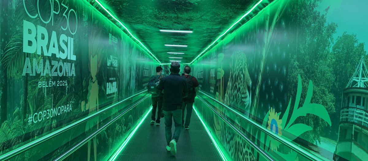 Los pasajeros caminan por una puerta de embarque que muestra el logotipo de la COP30