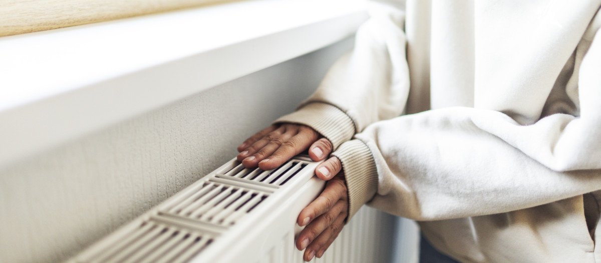 Mujer calentando sus manos en un radiador