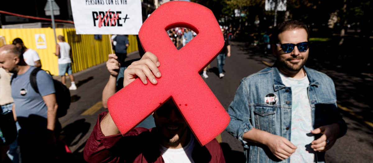Manifestantes portan un lazo rojo y pancarta con lema 'Por los derechos de las personas con VIH'