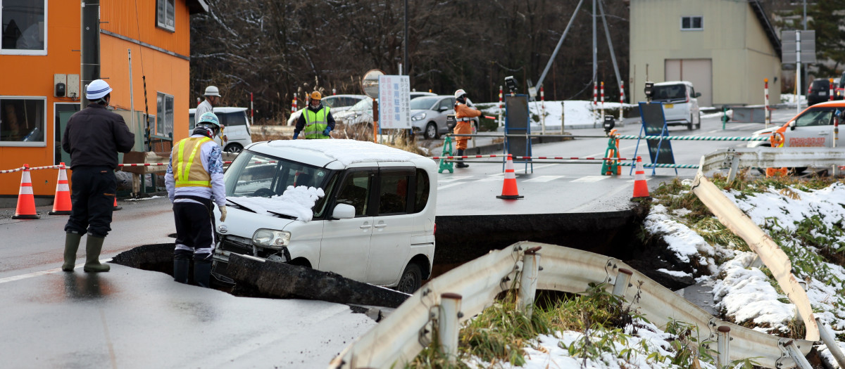 Trabajadores se reúnen junto a una carretera derrumbada en Tohoku, prefectura de Aomori, noreste de Japón