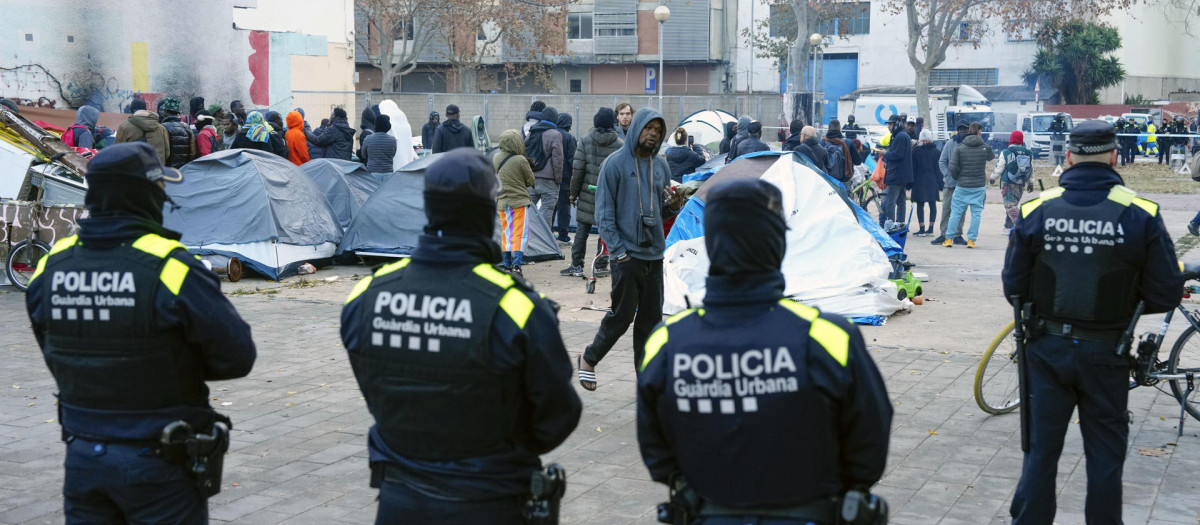 Agentes de la Policía Local de Badalona (Barcelona) controlan a los inmigrantes desalojados del antiguo instituto B9 de Badalona