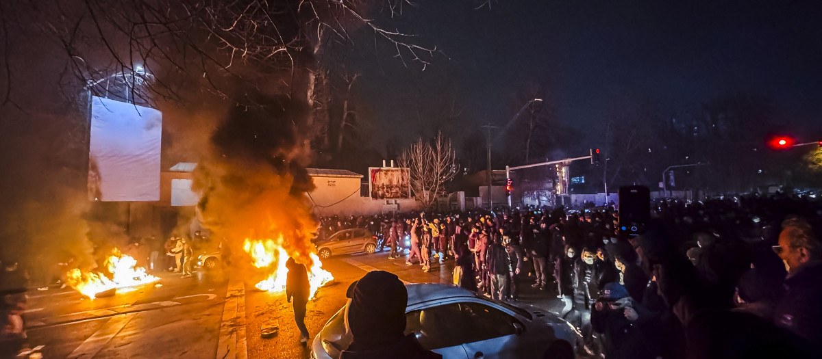 Iraníes se congregan mientras bloquean una calle durante una protesta en Teherán, Irán