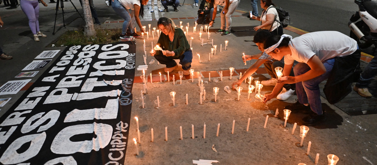 Familiares de presos políticos encienden velas en una vigilia para exigir la liberación de sus seres queridos, cerca de El Helicoide