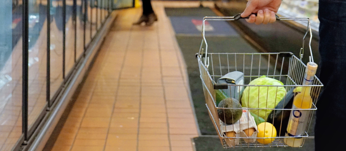 Gente comprando en un supermercado con la cesta de la compra