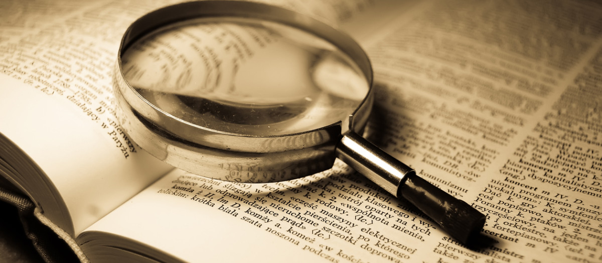 Imagen de una lupa sobre un diccionario