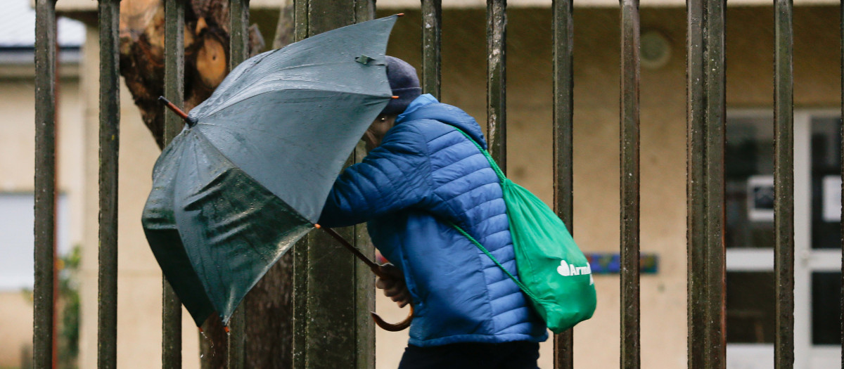A Mariña, Lugo. La Xunta de Galicia suspende las clases en la comarca lucense de A Mariña debido a la entrada de la borrasca Ivo, que deja fuertes vientos en tierra en la comarca. En la imagen, una mujer sujeta el paraguas con fuerza al pasar frente al IES Gregorio Sanz, en Ribadeo, en la mañana del miércoles 29 de enero