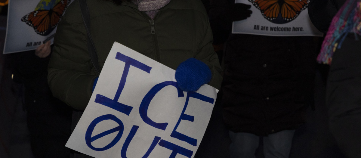 Una mujer sostiene una pancarta que dice «Fuera ICE»