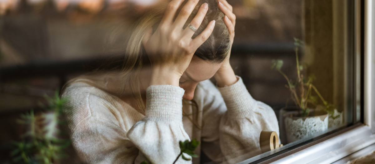 Young woman in depression. Portrait of her through a window.