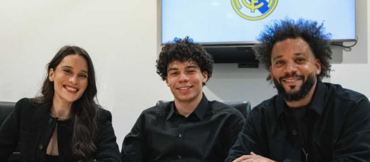 Enzo Alves, en el centro de la imagen, posa con sus padres tras firmar su primer contrato profesional con el Real Madrid