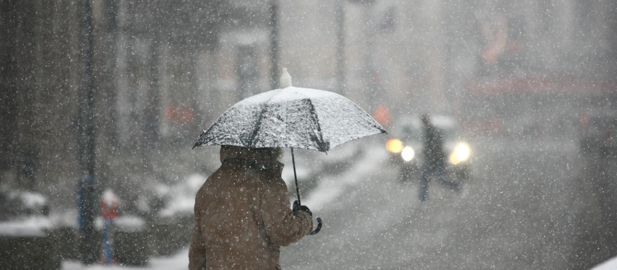 Man with umbrella during snow storm in the street