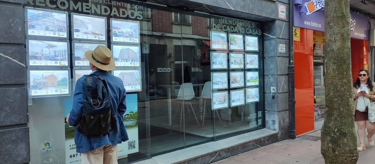 Un hombre mira anuncios de una inmobiliaria en Oviedo.