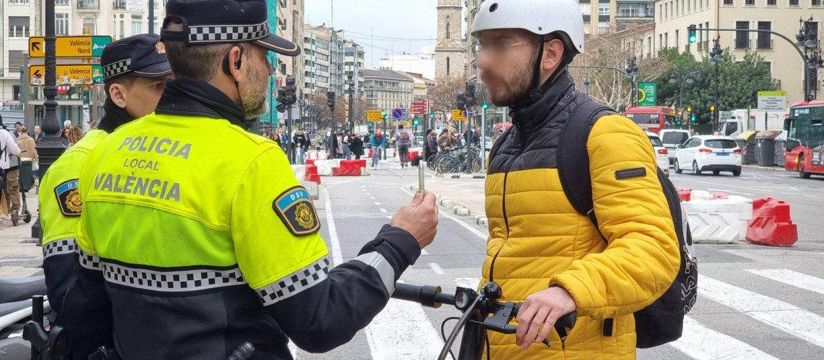 Imagen de archivo de un policía local hablando con un usuario de patinete eléctrico en el centro de Valencia