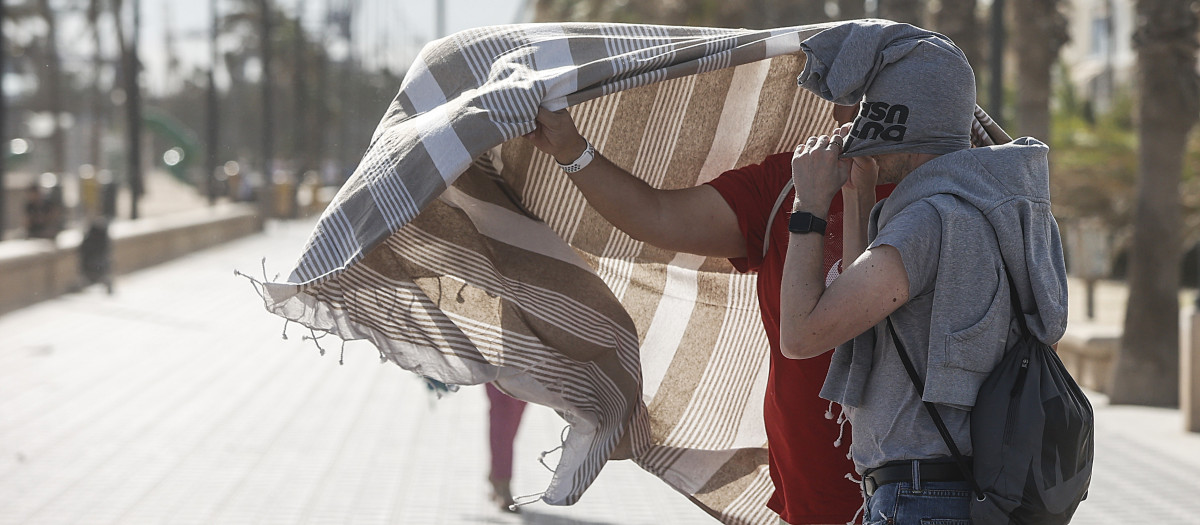 Imagen de dos personas protegiéndose del viento en Valencia