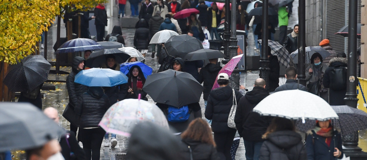 Personas caminan por la calle con paraguas en Madrid